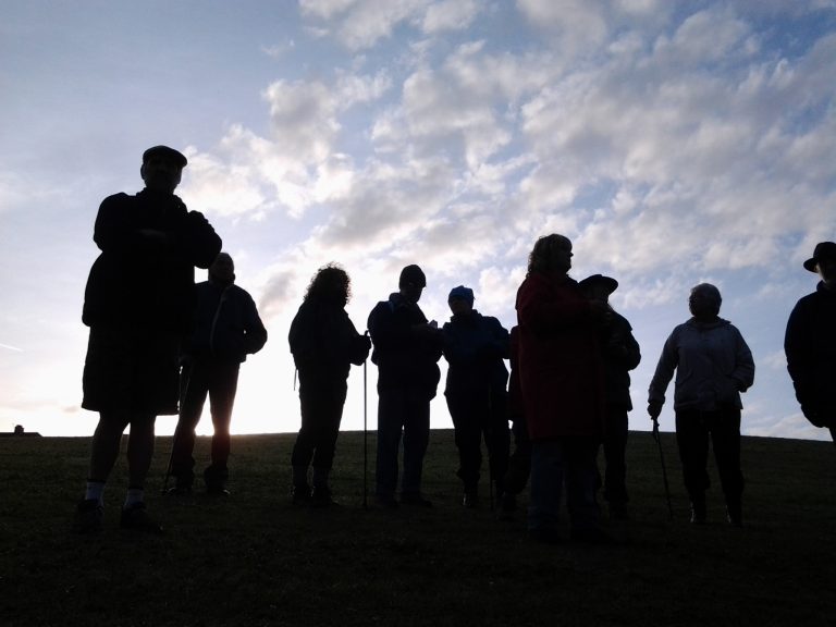 silhouettes of people in front of a partially cloudy sky